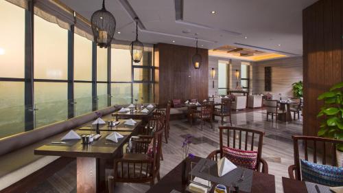 um restaurante com mesas e cadeiras de madeira e janelas em SSAW Boutique Hotel Delan Mogan Mountain em Deqing