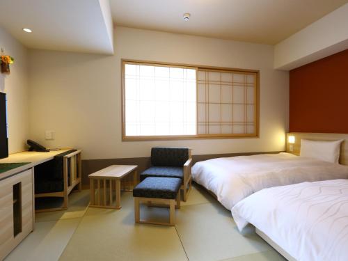 ein Hotelzimmer mit 2 Betten und einem Stuhl in der Unterkunft Onyado Nono Sendai Natural Hot Spring in Sendai