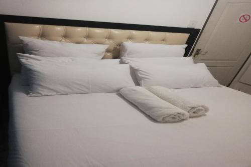 a white bed with white sheets and pillows at Maluti Backpackers in Phuthaditjhaba
