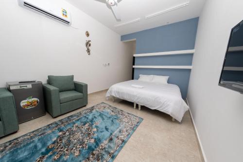 a bedroom with a bed and a green chair at استراحة نادي اورجان Orjan Guest House in Camp