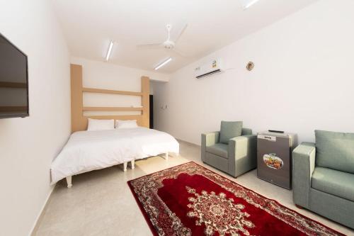 a bedroom with a bed and two chairs at استراحة نادي اورجان Orjan Guest House in Camp