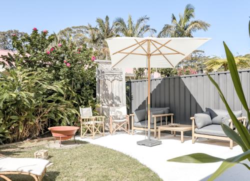 a patio with chairs and an umbrella at Casa Keys Shoal Bay in Shoal Bay