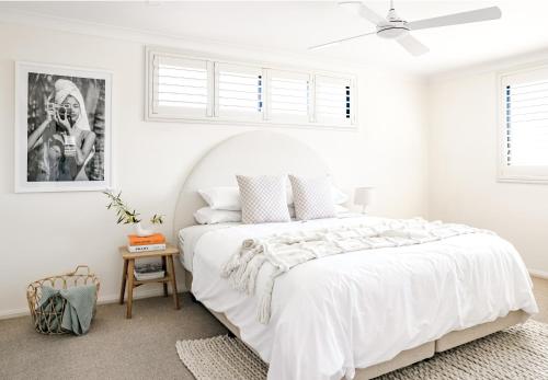 a white bedroom with a white bed and a ceiling fan at Casa Keys Shoal Bay in Shoal Bay
