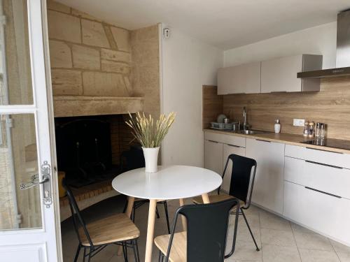 une cuisine avec une table et des chaises ainsi qu'une cheminée dans l'établissement La Madeleine, nichée au cœur de Saint-Émilion, à Saint-Émilion