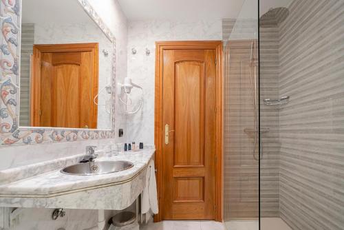 y baño con lavabo y ducha acristalada. en Hotel Corregidor, en Segovia