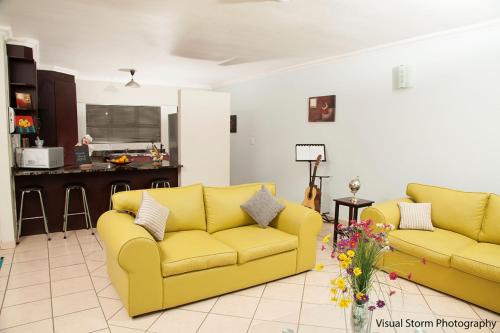 a living room with two yellow couches and a kitchen at Palm Valley Inn in Hartbeespoort