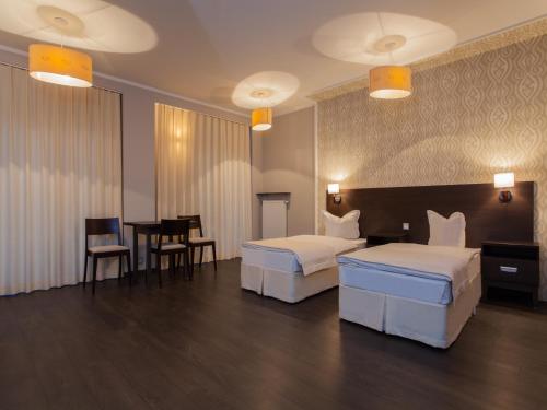 トゥシンにあるHotel Grzegorzewskiのベッド2台、テーブルと椅子が備わるホテルルームです。
