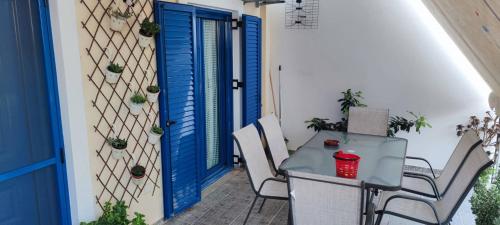 Tavari的住宿－TAVARI HOUSE 1，门廊上的一张桌子和椅子,门廊上设有蓝色的门