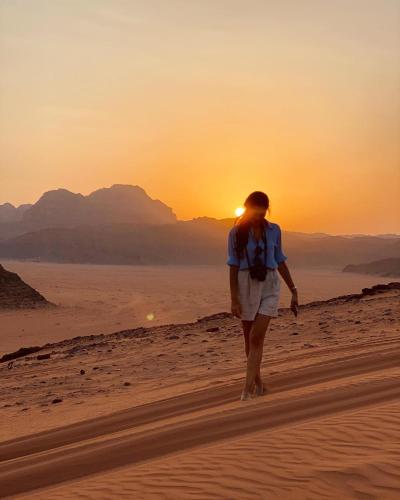 a woman walking in the desert at sunset at RUM STARDUST lUXURY CAMP in Wadi Rum