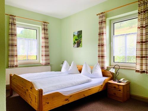 a bedroom with a wooden bed with two windows at Pension Weiberwirtschaft in Pobershau in Pobershau