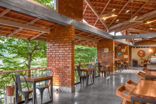 a restaurant with tables and chairs and a brick wall at Estate Stay - Riverside Coffee in Siddapur