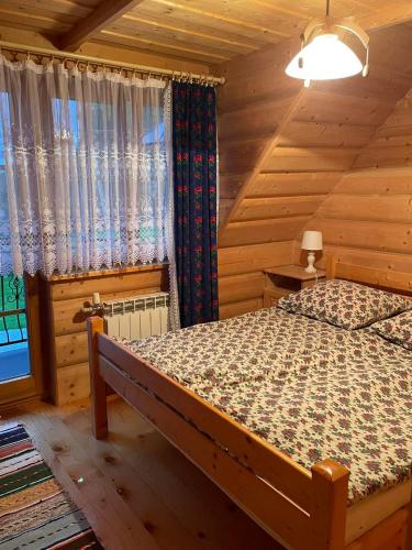 um quarto com uma cama num chalé de madeira em Góralski Apartament em Witów