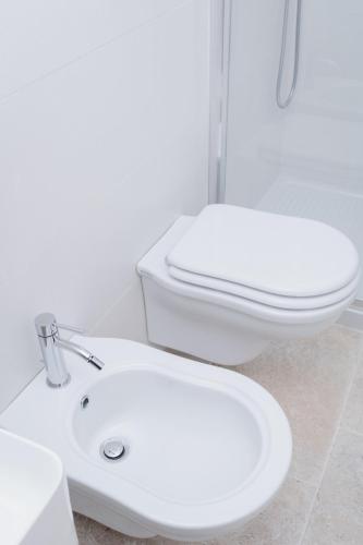 a white bathroom with a toilet and a sink at Palazzo Marzionna in Polignano a Mare