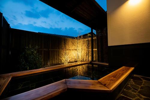 a hot tub in the backyard of a house at night at Kotonone Mai Suzu in Yufuin