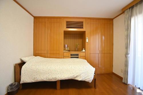1 dormitorio con 1 cama y armarios de madera en Private Beppu Tanoyu Onsen, en Beppu