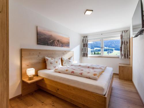 1 dormitorio con 1 cama con cabecero de madera y ventana en Ferienwohnung Bergliebe, en Scheffau am Wilden Kaiser