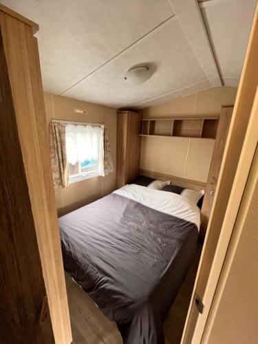 een kleine slaapkamer met een bed in een caravan bij Le Père André Hotton in Hotton