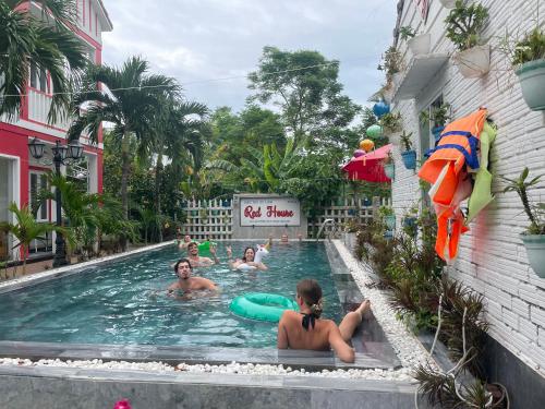 a group of people in a swimming pool at a hotel at Red House Homestay - Villa in Hoi An