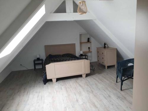 a attic bedroom with a bed and a chair at Logements Bonne Nouvelle in Rostrenen