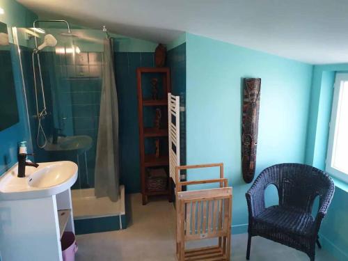 uma casa de banho com um lavatório, um chuveiro e uma cadeira. em Logements Bonne Nouvelle em Rostrenen