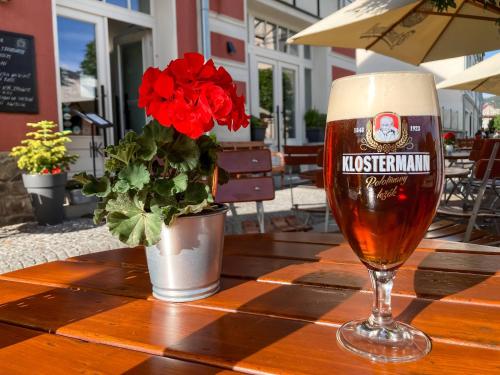 a glass of beer on a table with a vase of flowers at Apartman Hubert in Kašperské Hory