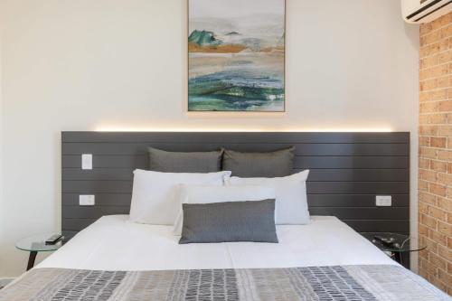 a bedroom with a white bed with a gray headboard at Coopers Colonial Motel in Brisbane
