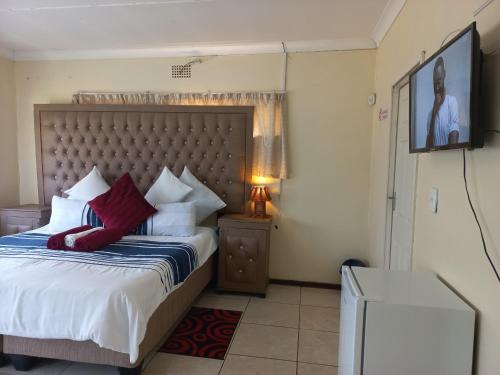 a bedroom with a bed and a tv on the wall at 26 Zea avenue Arcon Park Guest House in Vereeniging