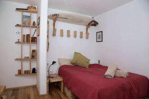 Full Apartment in the Heart of Roma Neighborhood في مدينة ميكسيكو: غرفة نوم مع سرير احمر مع لوح تزلج على الحائط