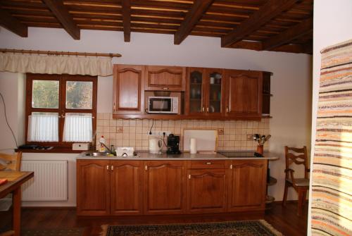 a kitchen with wooden cabinets and a microwave at Erdőszéli Vendégház - Mátraszentimre in Mátraszentimre