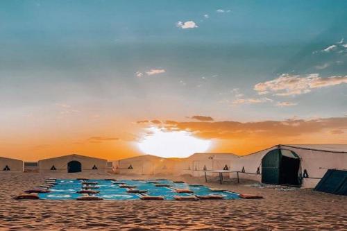 a group of tents on a beach with the sunset at Bivouac Draa in Zagora