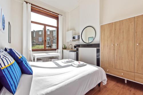 a bedroom with a white bed and a kitchen at The Old One Fifteen by Romy&Travis in Ghent