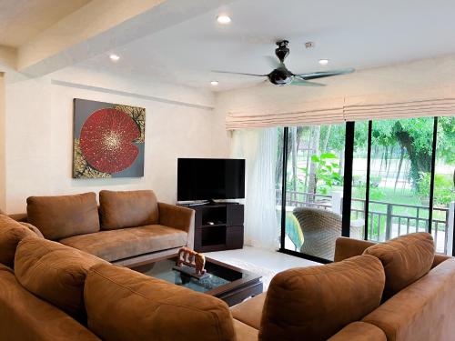 a living room with a couch and a flat screen tv at The Sands : 3 Bedrooms Naiharn Beachside Apartment in Nai Harn Beach
