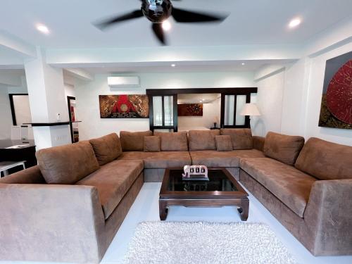 a living room with a brown couch and a table at The Sands : 3 Bedrooms Naiharn Beachside Apartment in Nai Harn Beach