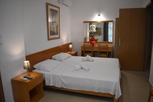 a bedroom with a white bed and a dining room at Hotel Ritsa in Kamena Vourla