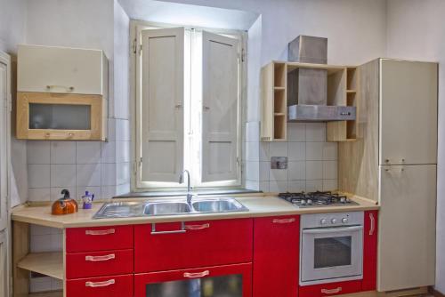 a kitchen with red cabinets and a sink at Borgo Creativo-A casa di Anna-Appartamento Mosaico. in Montopoli in Val dʼArno