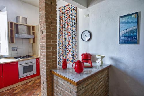 瓦爾迪安諾蒙托波利的住宿－Borgo Creativo-A casa di Anna-Appartamento Mosaico.，一间厨房,里面装有红色橱柜,墙上挂着一个时钟