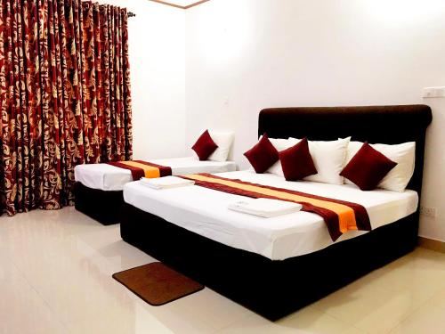 a bedroom with two beds with red pillows at New Rest House Inn in Mahiyangana
