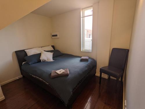 ein kleines Schlafzimmer mit einem Bett und einem Stuhl in der Unterkunft 2 bedroom apartment in the heart of the city! in Bendigo