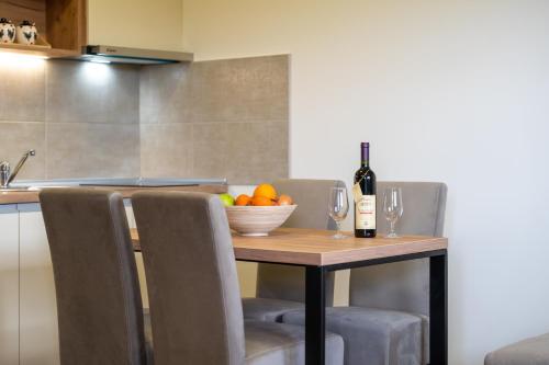 a table with a bowl of fruit and a bottle of wine at Monix Palace Zlatibor in Zlatibor