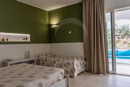 トッレ・ラピッロにあるVilla Sabbia Biancaの緑の壁のベッドルーム1室(ベッド2台付)