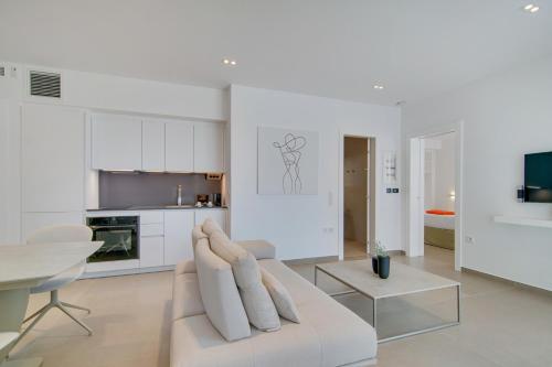a white living room with a white couch and a table at LIVINGHOME SUITES in Parga