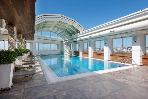 a large swimming pool in a building with a glass ceiling at Ramada Plaza By Wyndham Istanbul City Center in Istanbul