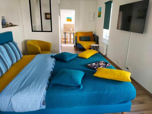 ein Schlafzimmer mit einem großen blauen Bett mit gelben Kissen in der Unterkunft la buffonnière in Montbard