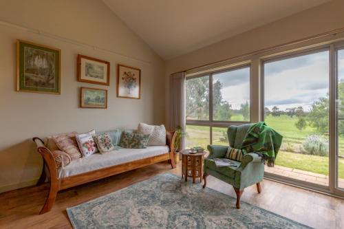 a living room with a couch and a chair and a window at Meander Retreat - The Green Room in Springton