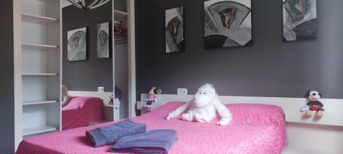 a bedroom with a pink bed with a stuffed animal on it at NALA HOUSE, acogedor,bien comunicado,aparcamiento gratis en la calle in Bilbao