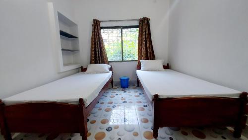 two beds in a room with a window at Nilam Guest House in Bodh Gaya