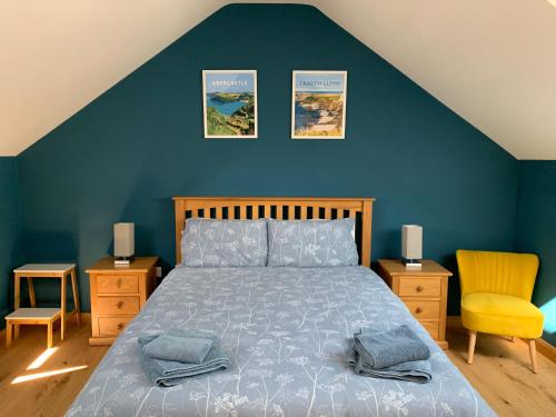 1 dormitorio con cama y pared azul en Cuddfan Fach - Pembrokeshire Stunning Barn near the Coastal Path en Abercastle