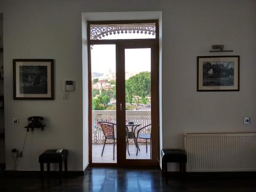 a room with a door open to a balcony with a table at Millennium Tbilisi in Tbilisi City