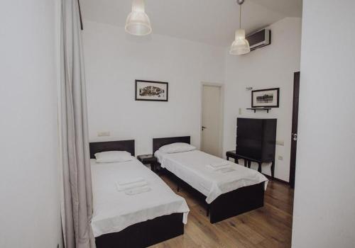 a room with two beds and a chair in it at Millennium Tbilisi in Tbilisi City