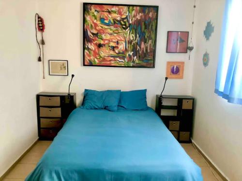 a bedroom with a blue bed and a painting on the wall at Cozy & Full Apt in Coyoacan Great for Long Stays in Mexico City